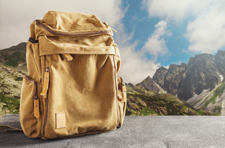 Photo hipster yellow backpack on the table against the mountains. hiking in the mountains concept