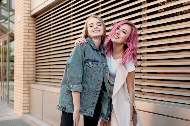 Hipster young adult friends embracing while hanging out in the city two young women laughing and walking enjoying carefree vacation lifestyle