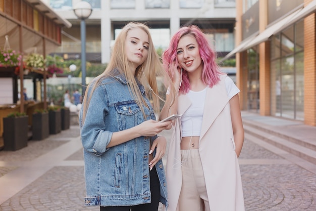 Hipster young adult friends embracing while hanging out in the city. Two young women laughing and walking enjoying carefree vacation lifestyle