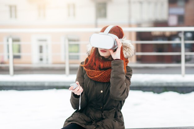 Hipster 어린 소녀는 현대 VR 안경 야외에 연결된 스마트 폰에서 가상 현실 모바일 게임 앱을 재생합니다.