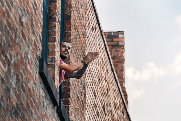 Hipster young male adult applauding from his balcony or window to support medical healthcare during Coronavirus pandemic