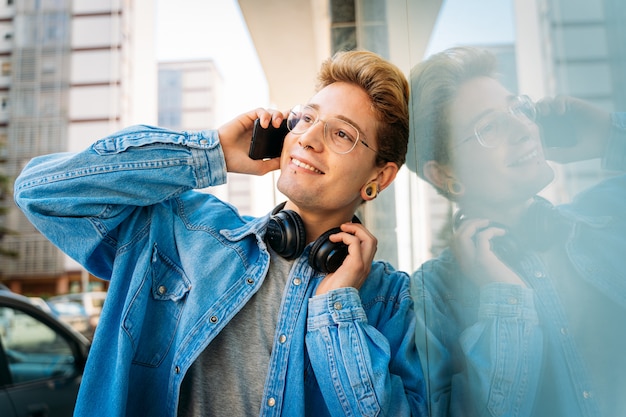 流行に敏感な若い男が彼の電話で話しながらよそ見。