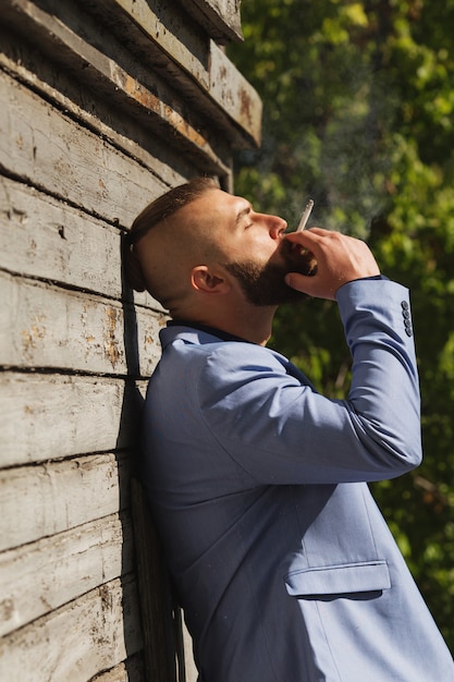 Hipster young man looking away from the camera while smoking a cigarette