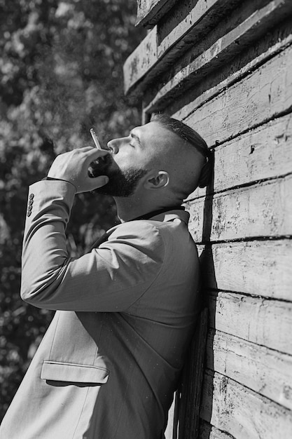 Photo hipster young man looking away from the camera while smoking a cigarette