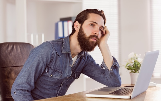 Hipster zakenman verveeld aan zijn bureau