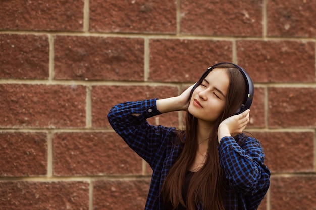 Hipstermeisje geniet van favoriete muzieknummer in draadloze koptelefoon