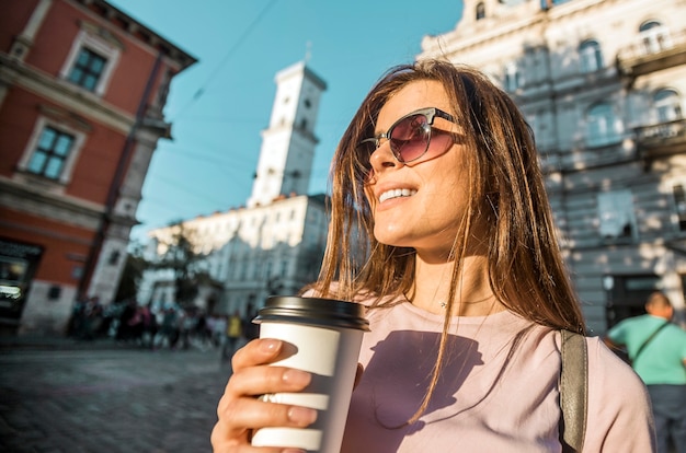 Hipstermeisje in zonnebril die koffiekop houden