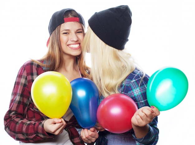 Hipstermeisjes die en gekleurde ballons glimlachen houden