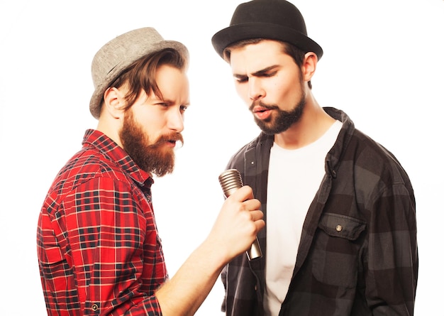 Hipsters: two young mens singing with microphone. Isolated on white.