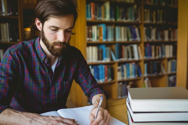 Hipsterstudent die in bibliotheek bestudeert