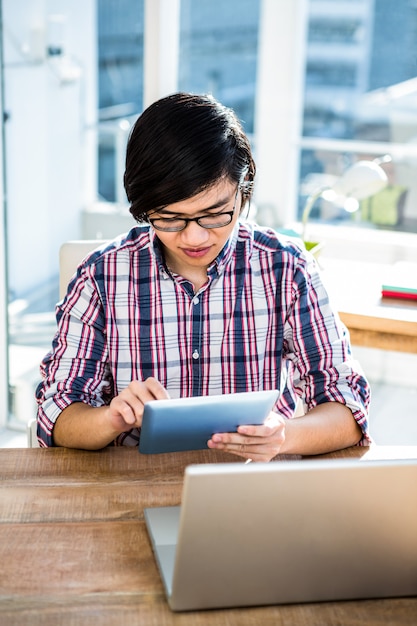 Hipsterzakenman die tablet in bureau gebruiken