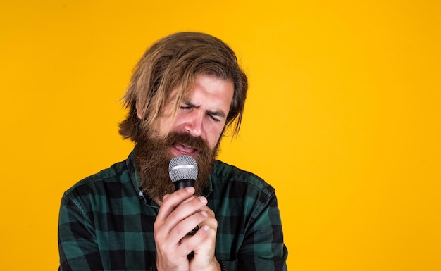 His favorite song rock music male karaoke singer mature charismatic male vocalist guy with beard singing in microphone confidence and charisma on stage bearded man wearing checkered shirt