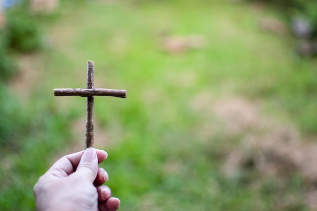 Photo his lefthand holding a cross right copyspace for entering text closeup photographing with background green and blurred