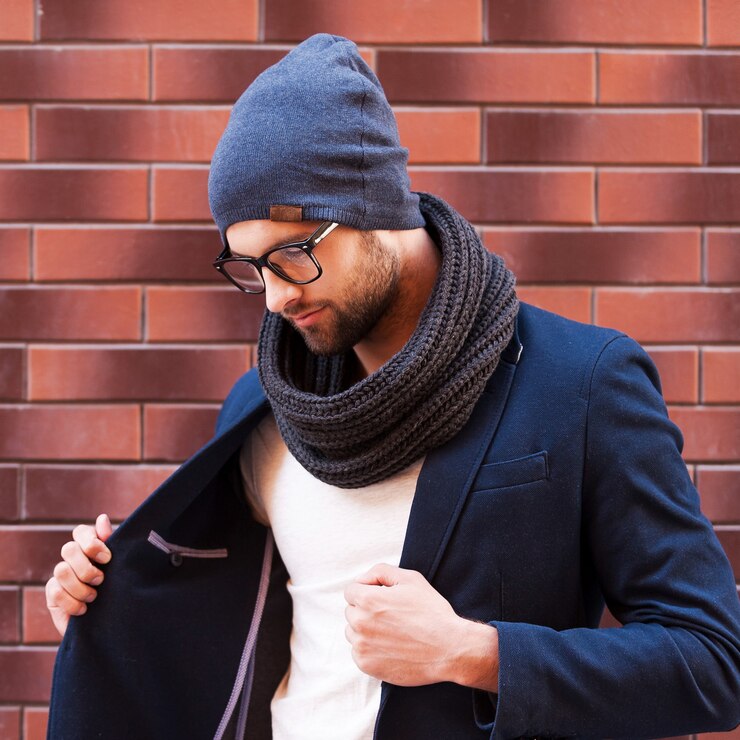 Photo in his own style. handsome young man in eyeglasses adjusting his jacket and away while standing against brick wall