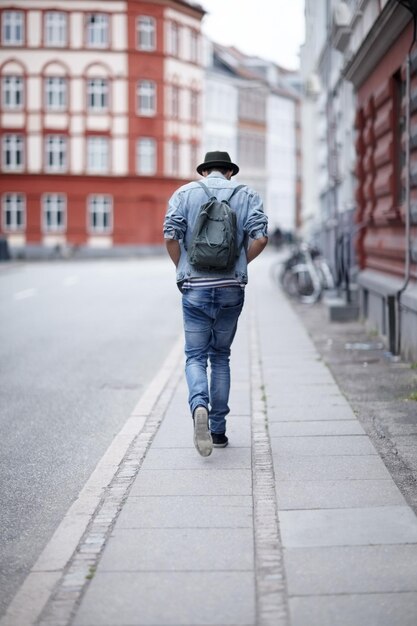 途中で街の通りを歩いている若い男の背面図