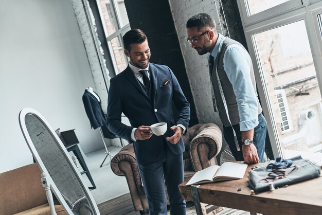 His work is his hobby. Young fashionable designer showing his client stylish suit 