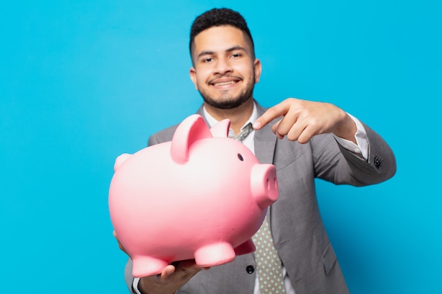 Hispanic businessman pointing or showing and holding a piggy bank