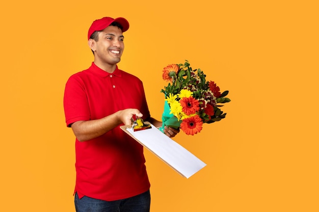 Hispanic deliveryman delivers flower bouquet in studio on yellow background