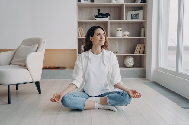 Hispanic female practices yoga meditates sitting on floor at home Stress relief healthy lifestyle