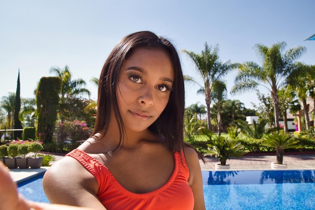 A Hispanic female with an orange swimsuit by pool