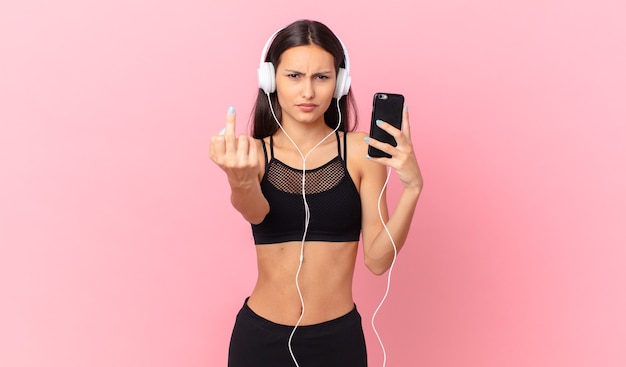 히스패닉 피트니스 여성은 헤드폰과 전화로 화가 나고 짜증이 나고 반항적이고 공격적입니다.
