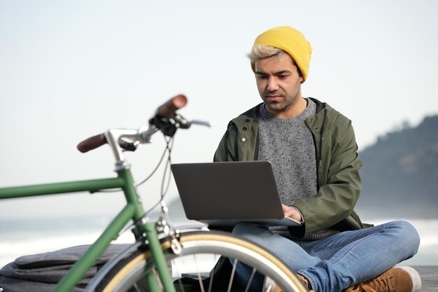 Hispanic freelance worker writing on his laptop outdoors