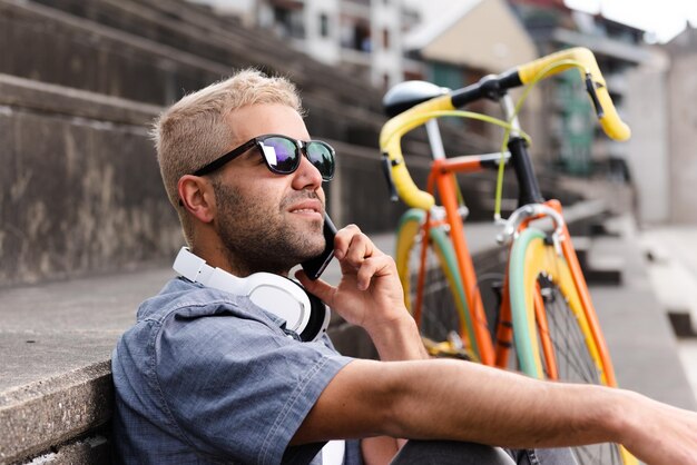Испаноязычный фрилансер со светлыми волосами разговаривает по телефону рядом со старинным велосипедом