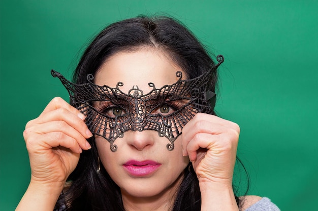 Photo hispanic girl hiding behind venetian mask on background green