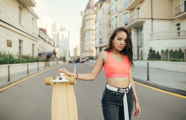 그녀의 손에 Longboard와 함께 포즈를 취하는 히스패닉계 여자