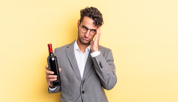 Hispanic handsome man feeling bored, frustrated and sleepy after a tiresome. wine bottle concept