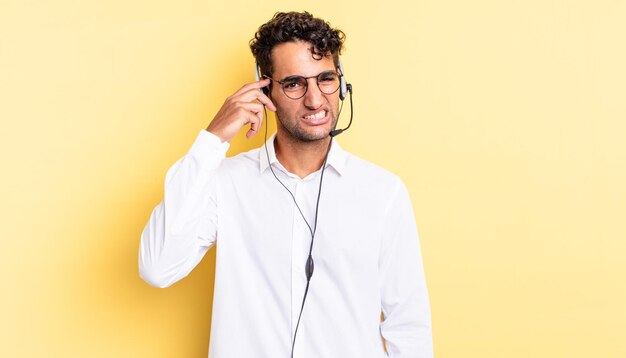 Hispanic handsome man feeling confused and puzzled, showing you are insane. telemarketer concept