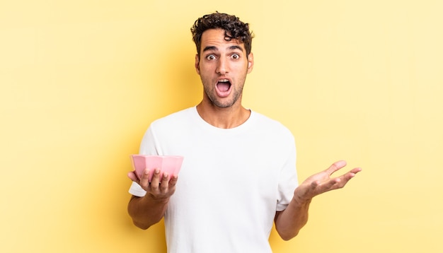 Hispanic handsome man feeling extremely shocked and surprised. empty bowl concept