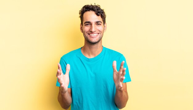 Hispanic handsome man feeling happy, astonished, lucky and surprised