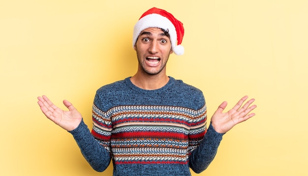 ヒスパニック系のハンサムな男は、信じられないほどの何かに幸せと驚きを感じています。クリスマスのコンセプト