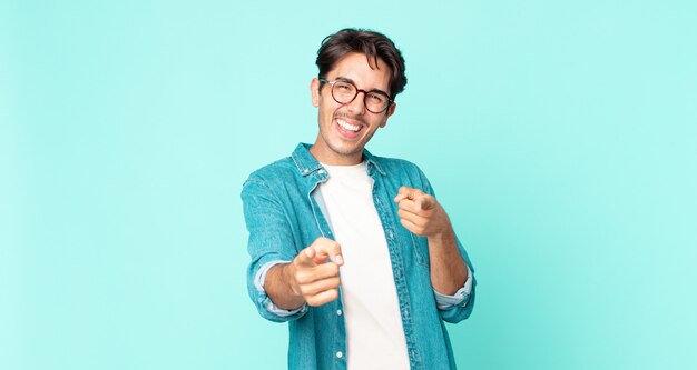 hispanic handsome man feeling happy, cool, satisfied, relaxed and successful, pointing at camera, choosing you