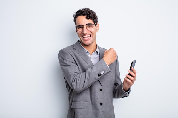 Hispanic handsome man feeling happy and facing a challenge or celebrating. business and phone concept