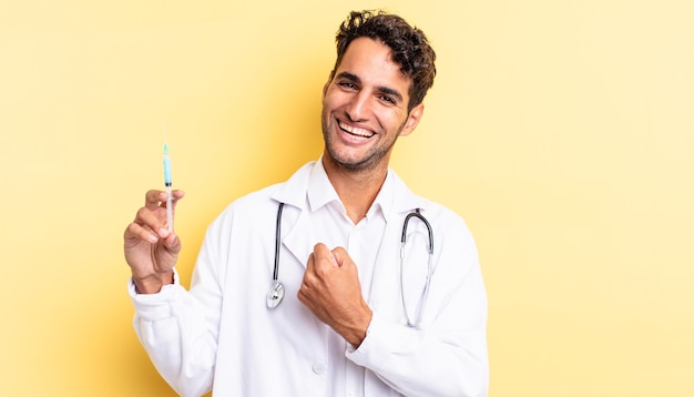 Hispanic handsome man feeling happy and facing a challenge or celebrating physician and srynge concept