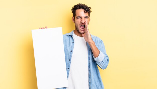 Hispanic handsome man feeling happy,giving a big shout out with hands next to mouth. empty canvas concept