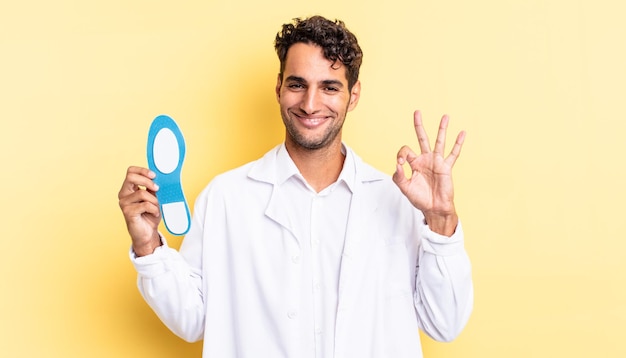 Hispanic handsome man feeling happy, showing approval with okay gesture. chiropodist concept