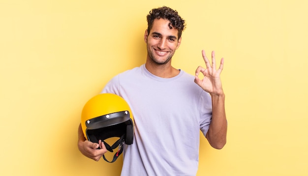 Hispanic handsome man feeling happy, showing approval with okay gesture. motorbike helmet concept