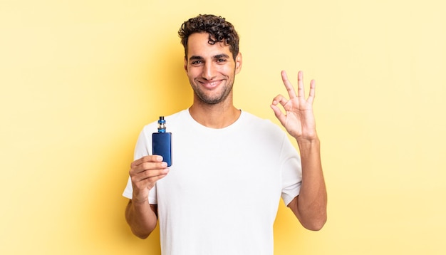 Hispanic handsome man feeling happy, showing approval with okay gesture. vaporizer concept