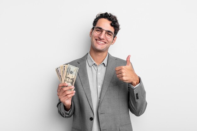 Hispanic handsome man feeling proud,smiling positively with thumbs up. business and dollar banknotes concept