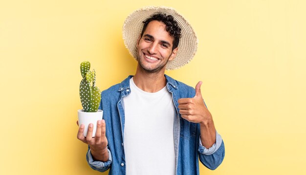 Hispanic handsome man feeling proudsmiling positively with thumbs up farmer and cactus concept