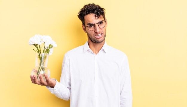 Hispanic handsome man feeling puzzled and confused. flowers pot concept