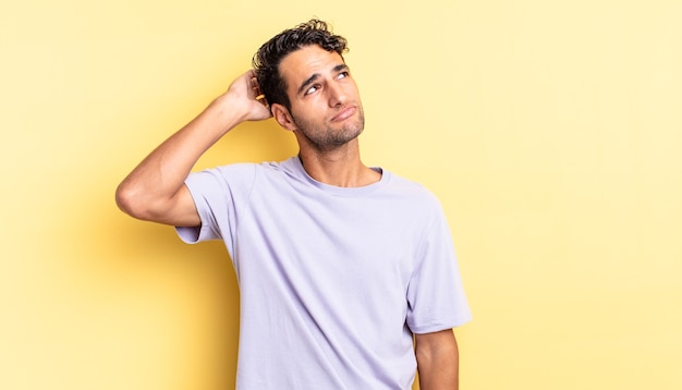 hispanic handsome man feeling puzzled and confused, scratching head