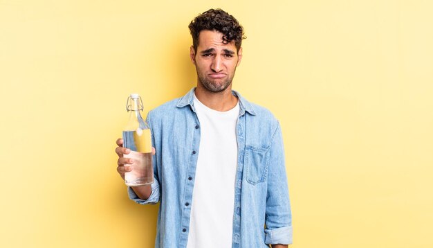 Hispanic handsome man feeling sad and whiney with an unhappy look and crying. water bottle concept