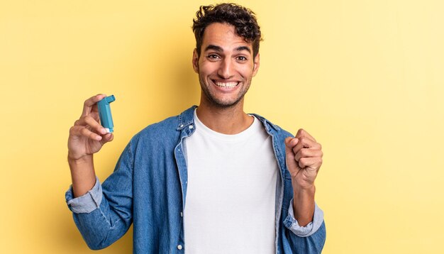 Hispanic handsome man feeling shocked,laughing and celebrating success. asthma concept