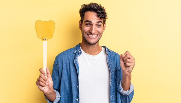 Hispanic handsome man feeling shocked,laughing and celebrating success. kills flies concept