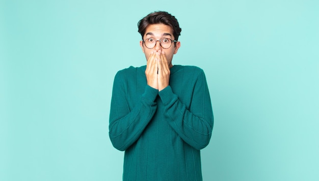 Hispanic handsome man feeling worried, upset and scared, covering mouth with hands, looking anxious and having messed up