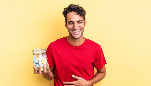 Hispanic handsome man laughing out loud at some hilarious joke. candies concept